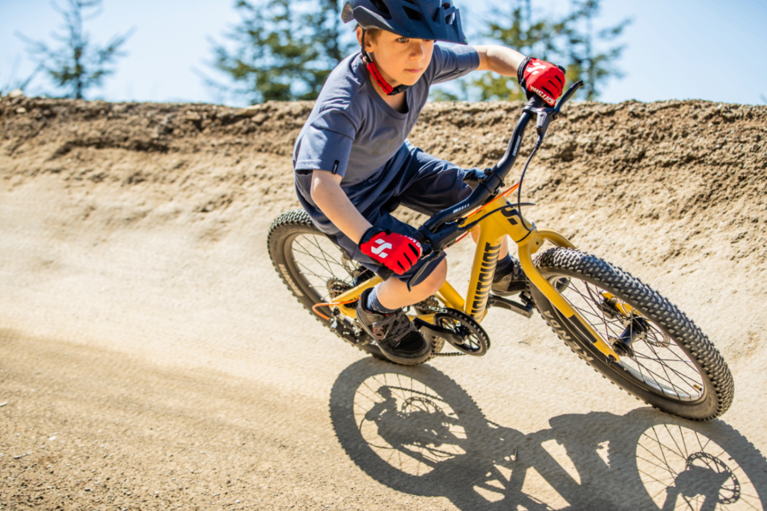 Barn på sandfarvet Eightshot mountainbike i sving på pumptrack